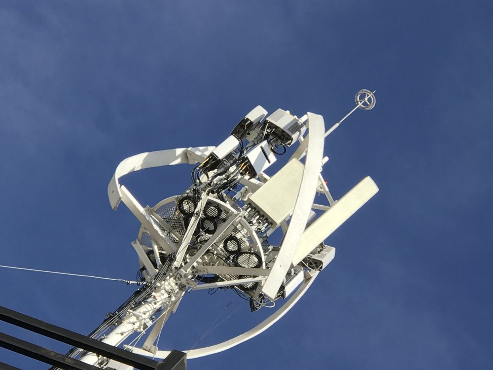 Engineers working together to install and inspect radio communication equipment on a rooftop overlooking a city skyline, focused and collaborative atmosphere, no visible text in the image